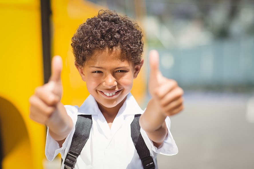 elementary school boy smiles and gives 2 thumbs up